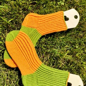 welniane-skarpety-handmade Zbliżenie na unikalny splot ręcznie dzierganych skarpet, ukazujące jakość i grubość podwójnej nitki wełny skarpetkowej w kolorach pomarańczu i zieleni.